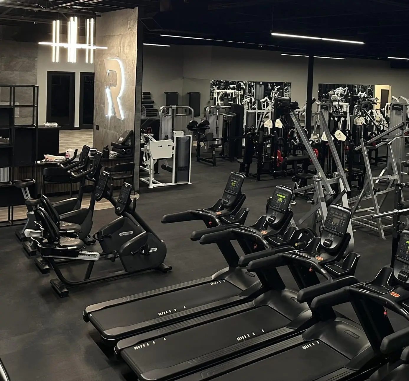 The Rhein Athletic Club cardio deck, treadmills and ellipticals lined up beneath a backlit R logo.
